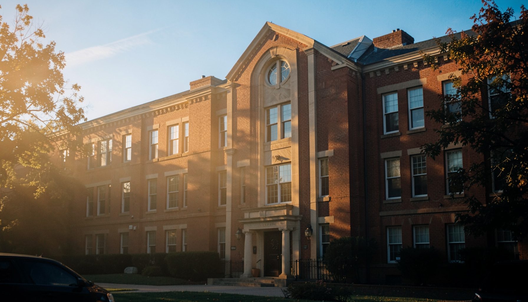 Warm golden-hour photo of a college campus building facade bathed in soft amber light